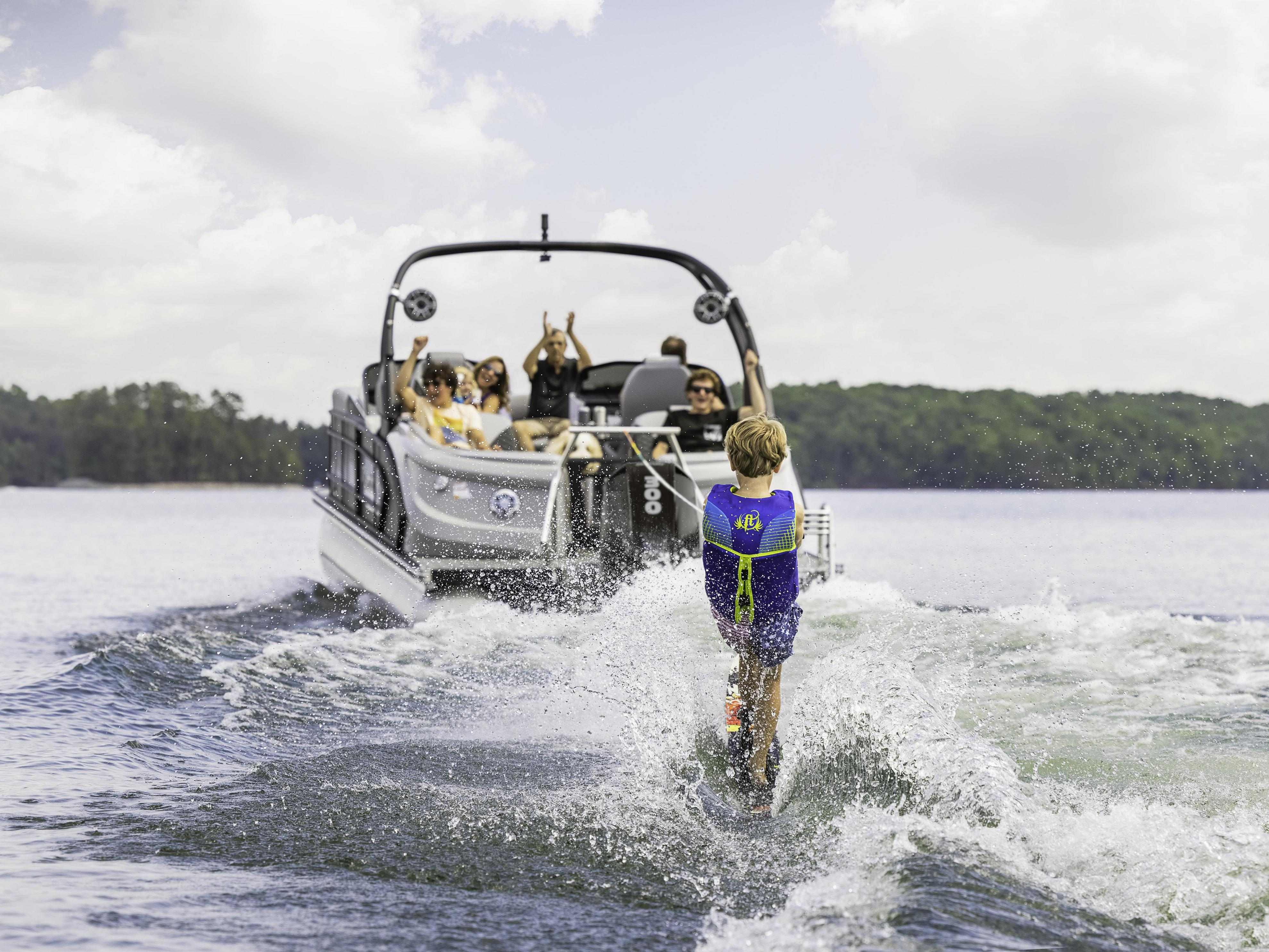 Un enfant fait du wakeboard derrière un Manitou LX conçu pour les sports nautiques