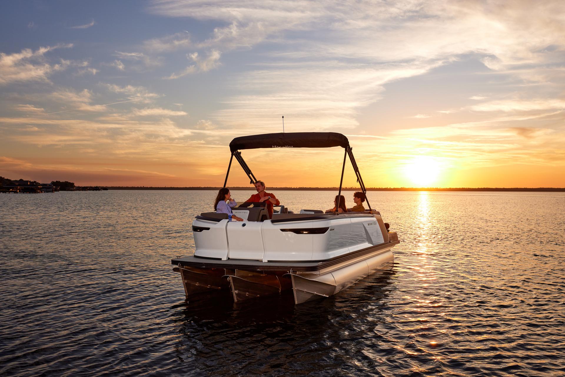 View of a family on a Manitou Cruise pontoon chatting under a sunset