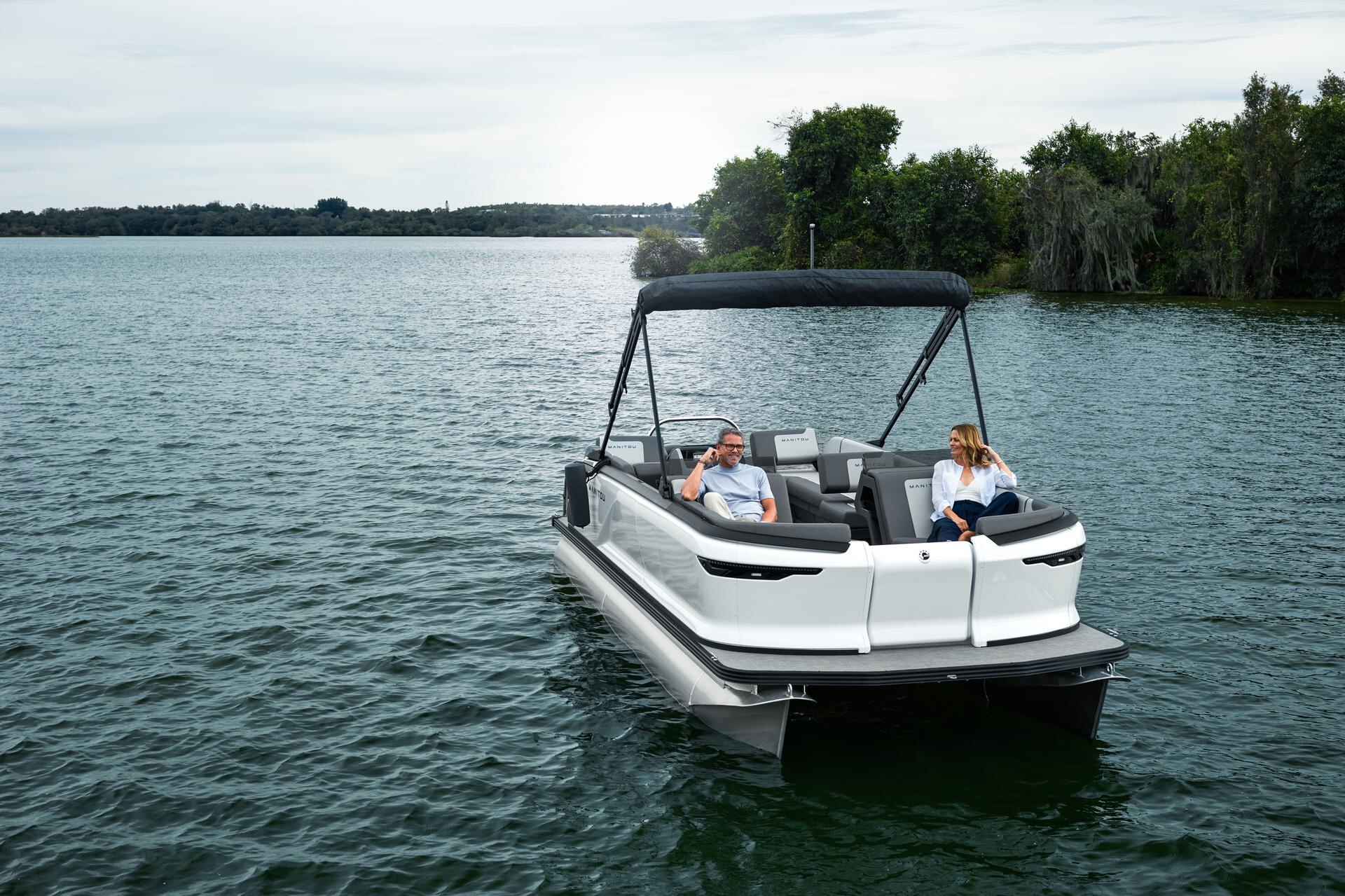 A man and a woman cruising in their Manitou Cruise with traditional outboard motor.