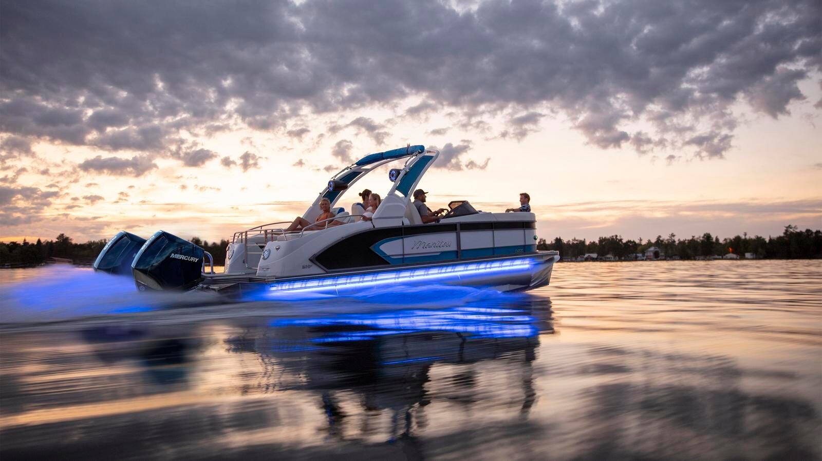 A group of friends sailing on a white and blue Manitou pontoon boat